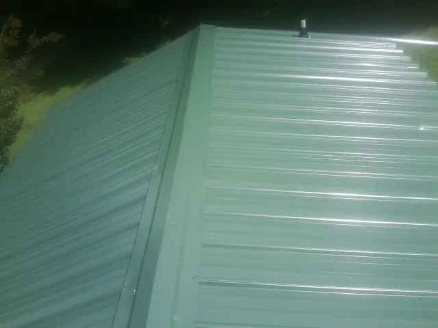 New green metal panels meeting at the ridge of a roof — Flat Roof Repair work by our crew in Dyke