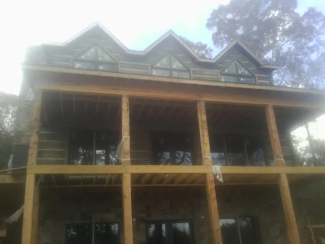 Dormers and porch framing on a large log home under construction — Roof Coating work by our crew in Dyke