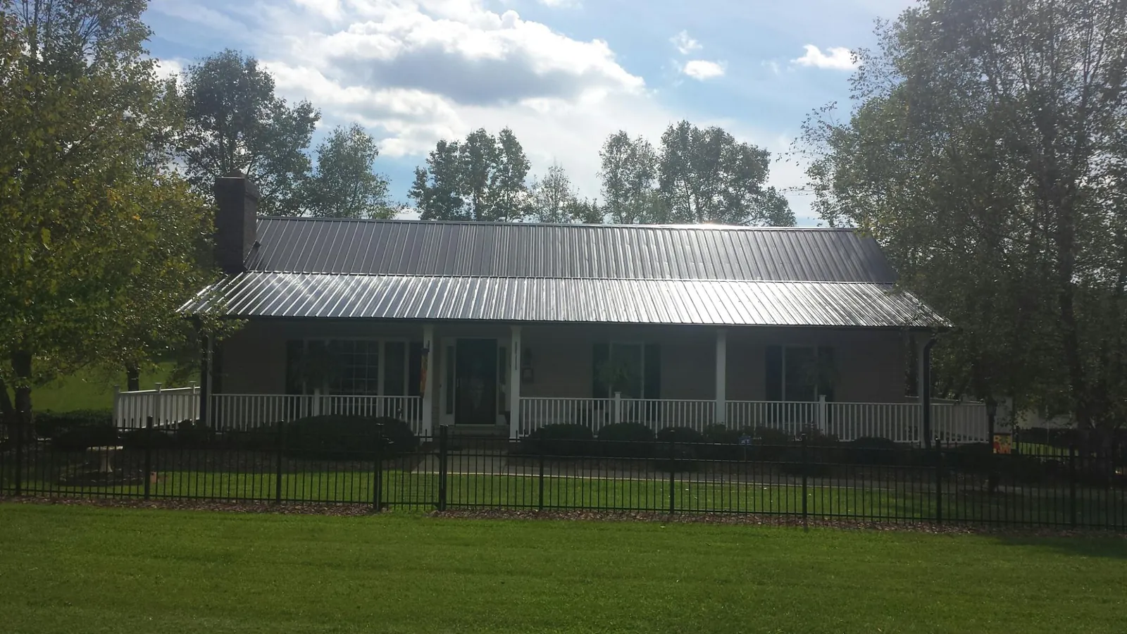 Gray metal roof on a brick ranch with a full width front porch — Gutter Guard Installation work by our crew in Dyke