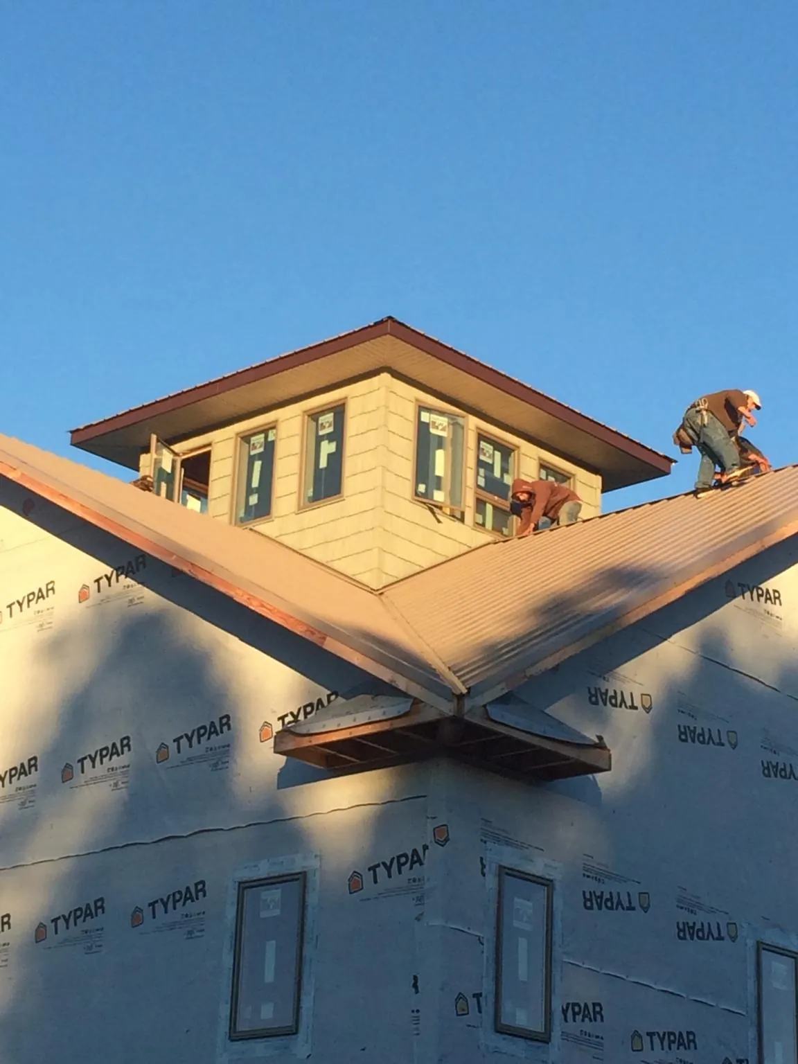 Roofers working around a rooftop cupola on a new metal roof at sunset — Roof Waterproofing in Dyke by Roofing Brothers